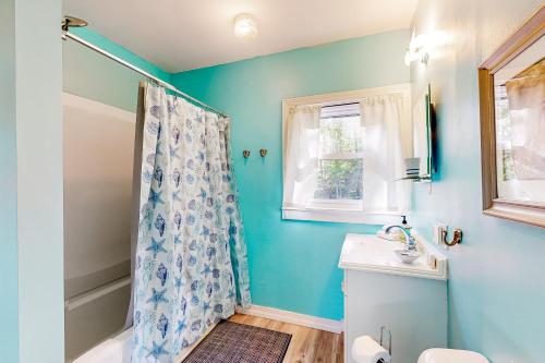 uma casa de banho azul com um chuveiro e um lavatório em Sea Bell Retreat em Phippsburg