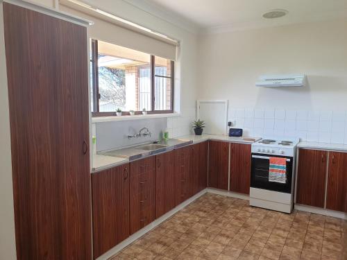 a kitchen with wooden cabinets and a sink and a stove at River House Mudgee in Mudgee