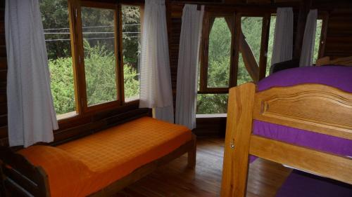 a bedroom with a bed and windows in a cabin at Rincón de los Troncos in Merlo
