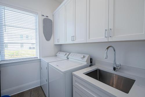 een witte keuken met een wastafel en een wasmachine bij Ocean Estate in Fort Pierce