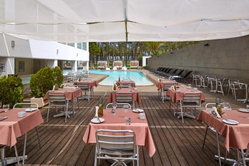 a patio with tables and chairs next to a swimming pool at Alcazar Hotel & SPA in Monte Gordo