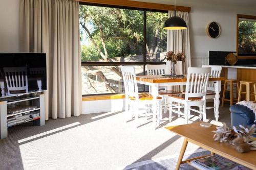 ein Wohnzimmer mit einem Tisch und Stühlen sowie einem großen Fenster in der Unterkunft Beach Break - Diamond Island in Bicheno