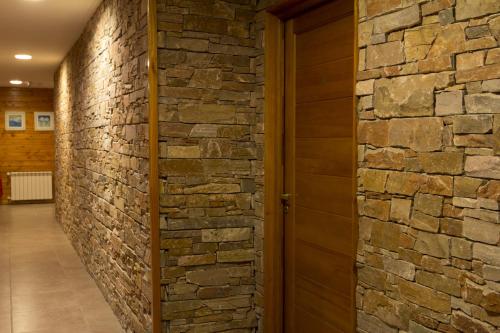 a hallway with a stone wall and a wooden door at Encanto del Rio in Villa La Angostura
