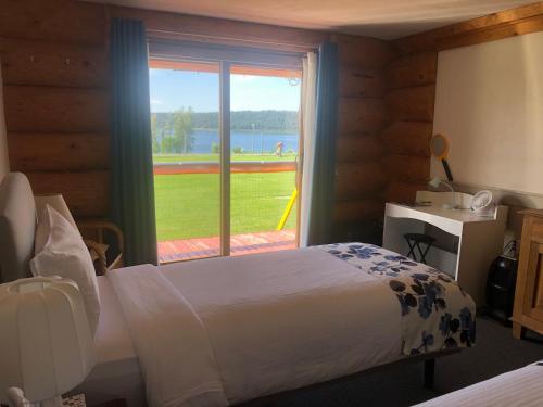 a bedroom with a bed and a window with a view at Cariboo Log Guest House in Lac La Hache