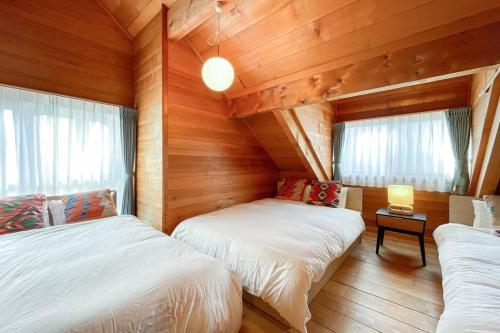 twee bedden in een kamer met houten wanden en ramen bij S-villa Karuizawa - the forest - in Kita-karuizawa