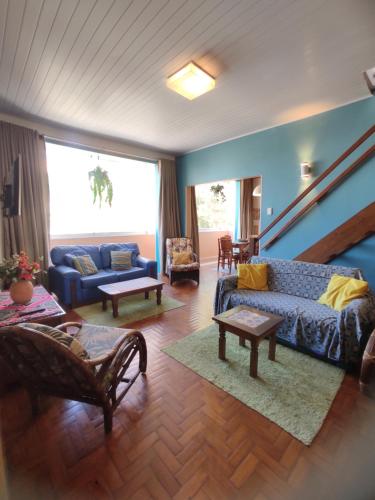 sala de estar con sofá azul y sillas en Grande 4Q com 2Suites e Terraço na Barra perto praias, en Salvador