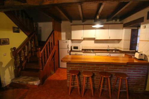 a kitchen with a counter and stools in a room at Alojamiento Rural Casa La Mata. in Cuñaba