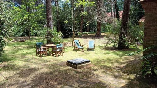 un patio trasero con mesa, sillas y parrilla en Casa Algarrobo Carilo en Cariló