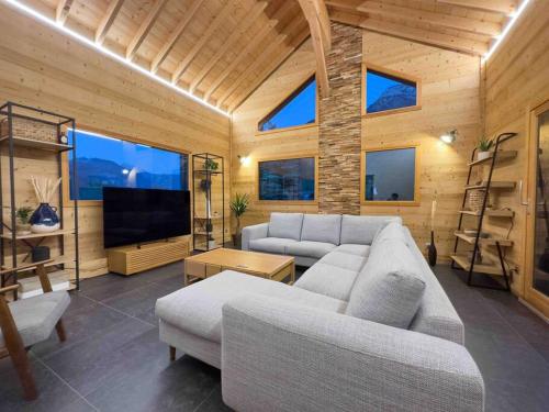 a living room with a couch and a tv at ⁂ Chalet Alizée · Nature, lac et montagnes ⁂ in Alex