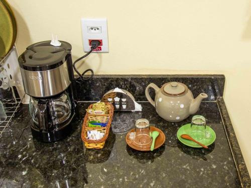 a counter top with a coffee maker and a tea kettle at Pousada & Glamping Terra de Aquários in Aiuruoca
