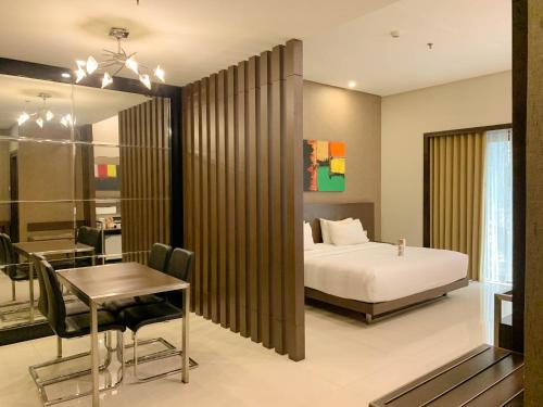 Savana Hotel & Convention Malang في مالانغ: غرفة نوم بسرير وطاولة طعام