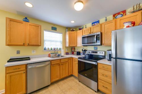 a kitchen with wooden cabinets and a stainless steel refrigerator at Condo with Deck Walk to Beach and Convention Center! in Wildwood