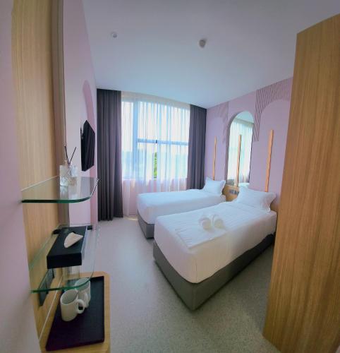 a hotel room with two beds and a glass table at Wellesley Hotel in Simpang Ampat