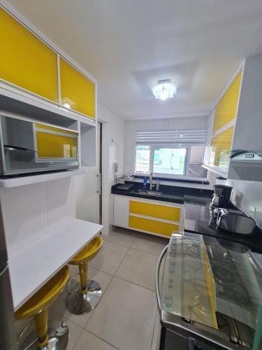 a kitchen with yellow and white cabinets and a counter at Arraial do Cabo, Vista mar, conforto, Piscina. in Arraial do Cabo
