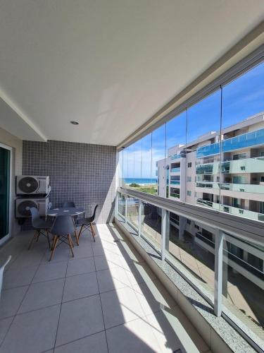 a large room with a balcony with a table and chairs at Arraial do Cabo, Vista mar, conforto, Piscina. in Arraial do Cabo