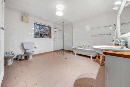 a bathroom with two toilets and a tub and a sink at Quigtoo Cottage in Berridale