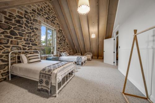 two beds in a room with a stone wall at Quigtoo Cottage in Berridale
