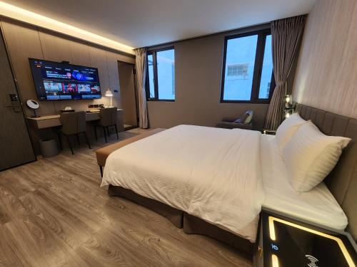 a hotel room with a large bed and a television at Hualien Pink Corner Hotel in Hualien City