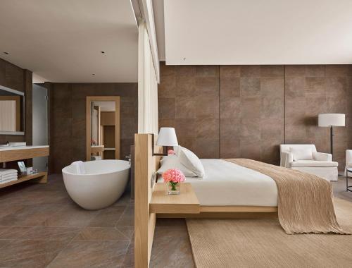 a bedroom with a large bed and a bath tub at The Sanya EDITION in Sanya