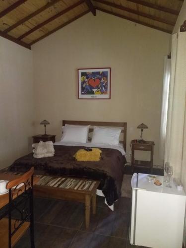 a bedroom with a large bed and two tables at Chalés das Orquídeas in Visconde De Maua