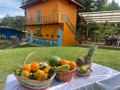 two baskets of fruit on a table in front of a house at EcoGranjasYa in El Peñol