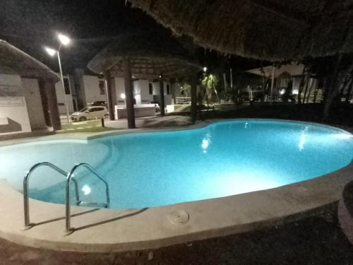 - une grande piscine bleue la nuit dans l'établissement Casa en privada con alberca, Excelente para vacaciones y descanso, à Playa del Carmen