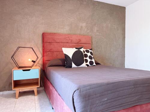 a bedroom with a bed with a red headboard and a side table at Casa Estadio en Guadalajara zona centro! in Guadalajara