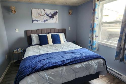 - une chambre avec un lit aux murs bleus et une fenêtre dans l'établissement Family Ties Vacation Home - Rossy House, à Twillingate