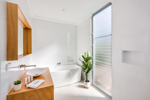Un baño blanco con bañera y lavabo. en Beach Life on Beach, en Dunsborough