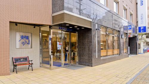 a store front with a bench in front of a building at Toyoko Inn Hamamatsu eki Kita guchi in Hamamatsu