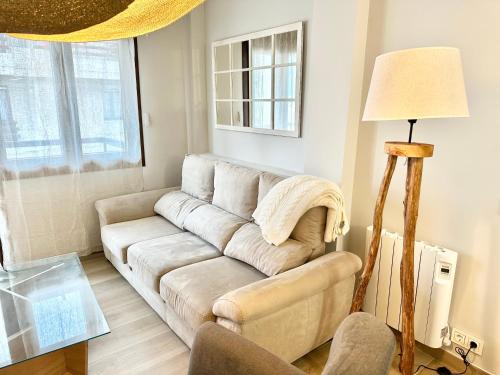 a living room with a couch and a lamp at Apartamentos Noja Playa in Noja