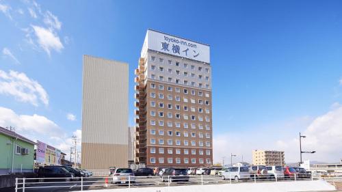 a tall building with a sign on top of it at Toyoko Inn Higashi hiroshima Ekimae in Higashihiroshima