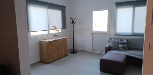 sala de estar con sofá, tocador y 2 ventanas en Comfort Apartments, en Kefalos