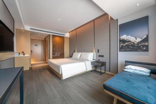 - une chambre avec un lit et un canapé dans l'établissement Atour Hotel Wuxi New District Nanchan Temple Scenic Area, à Wuxi