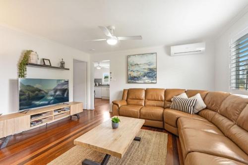 a living room with a brown couch and a table at Convent Cottage - Pet-Friendly Central Yamba Escape - Holiday Yamba in Yamba