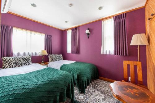 2 camas en una habitación de color púrpura y verde en S-villa Nasu Audrey en Nasu