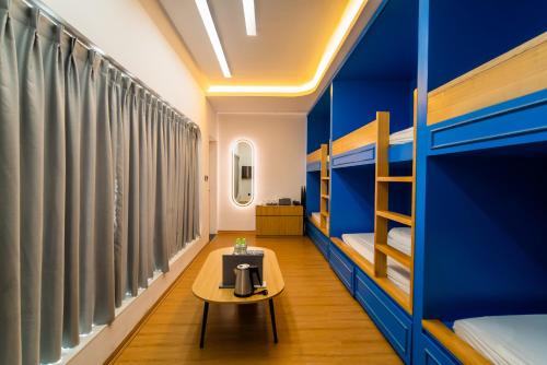 a room with blue walls and a table and bunk beds at Mộc Châu Island - The Bullet Hotel in Mộc Châu