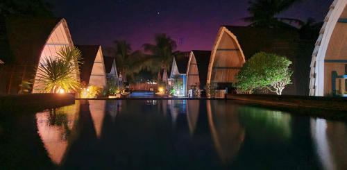 a house with a swimming pool at night at Youpy Bungalows in Gili Islands