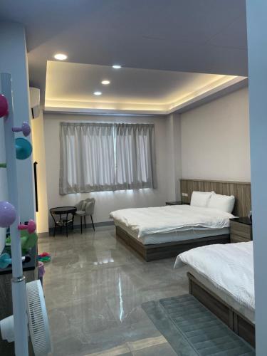 a bedroom with two beds and a table and a chair at 綠竹筍民宿 in Zhushan