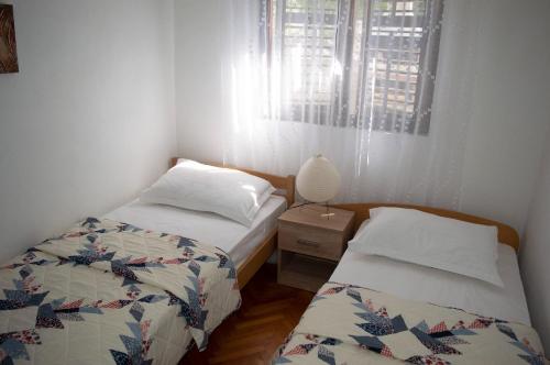 a bedroom with two beds and a lamp and a window at Apartment Ela - very close to beach in Rogač