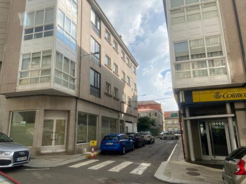 a city street with cars parked next to tall buildings at LALIN CENTRO URBANO, CÓMODO Y FUNCIONAL in Lalín