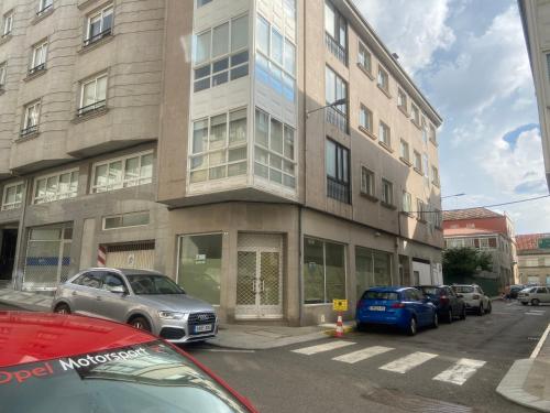 a building with cars parked in front of it at LALIN CENTRO URBANO, CÓMODO Y FUNCIONAL in Lalín