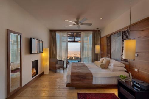 a bedroom with a bed and a living room with a fireplace at Beresheet by Isrotel Exclusive in Mitzpe Ramon
