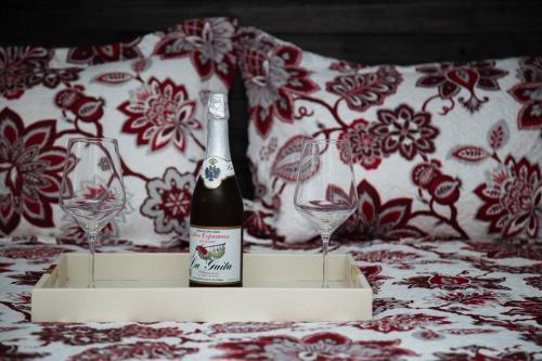una bottiglia di vino seduta su un letto con due bicchieri di private apartmento airport 7 minutes y de la playa a Carolina