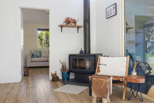 a living room with a fireplace and a chair at Fiery, cozy starry nights - Farm stay! in Bellthorpe