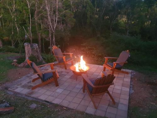 a fire pit with chairs and a table with a fire burns at Fiery, cozy starry nights - Farm stay! in Bellthorpe
