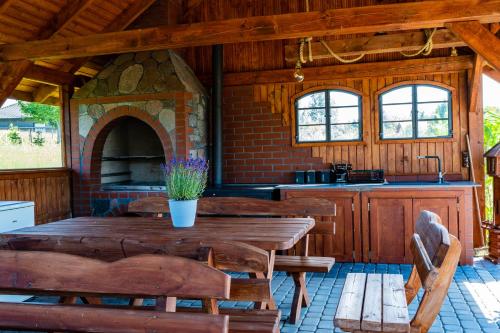 a kitchen with a wooden table and a stone oven at Domki Nad Stawem Mazury D5 in Mrągowo