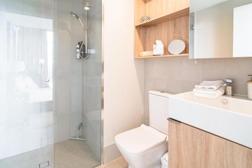 uma casa de banho com um WC e uma cabina de duche em vidro. em Lux 37th floor 2br 2bath, Infinity pool, Gym, Wifi em Brisbane