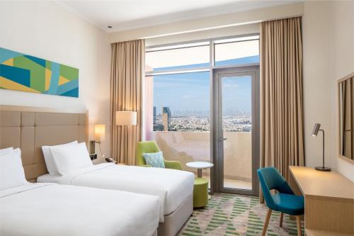Holiday Inn & Suites - Dubai Science Park, an IHG Hotel في دبي: غرفة فندقية بسريرين ونافذة