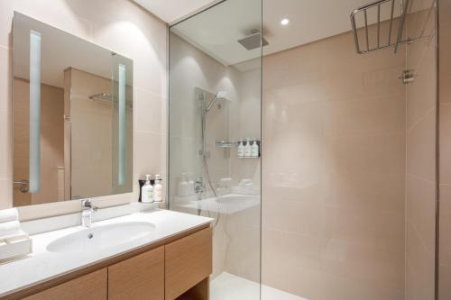 a bathroom with a sink and a shower at Holiday Inn & Suites - Dubai Science Park by IHG in Dubai